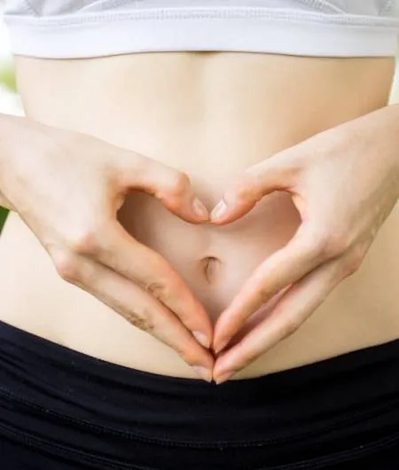 close-up-female-hands-shaping-heart-belly